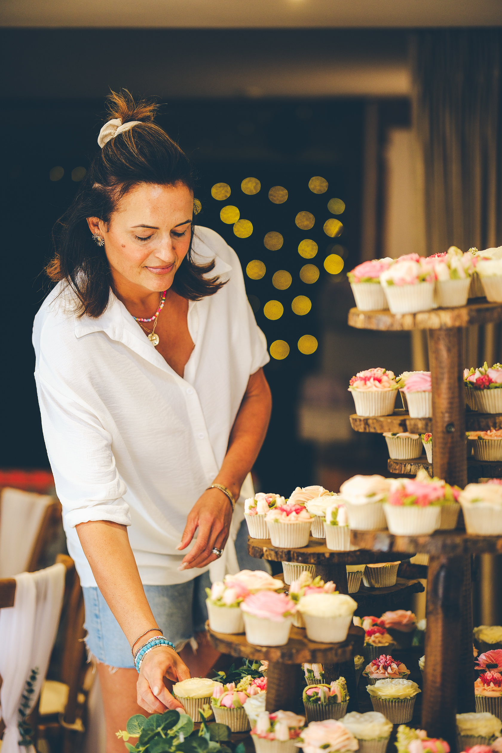 Emma arranging a tower of floral buttercream cupcakes at a wedding