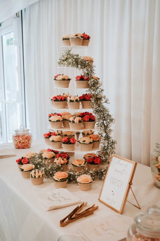 Tall wedding cupcake tower with coral and peach buttercream roses and trailing gypsophila