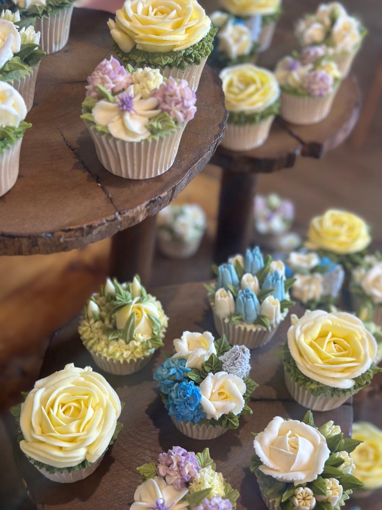 Pastel buttercream rose and hydrangea cupcakes on rustic wooden stands